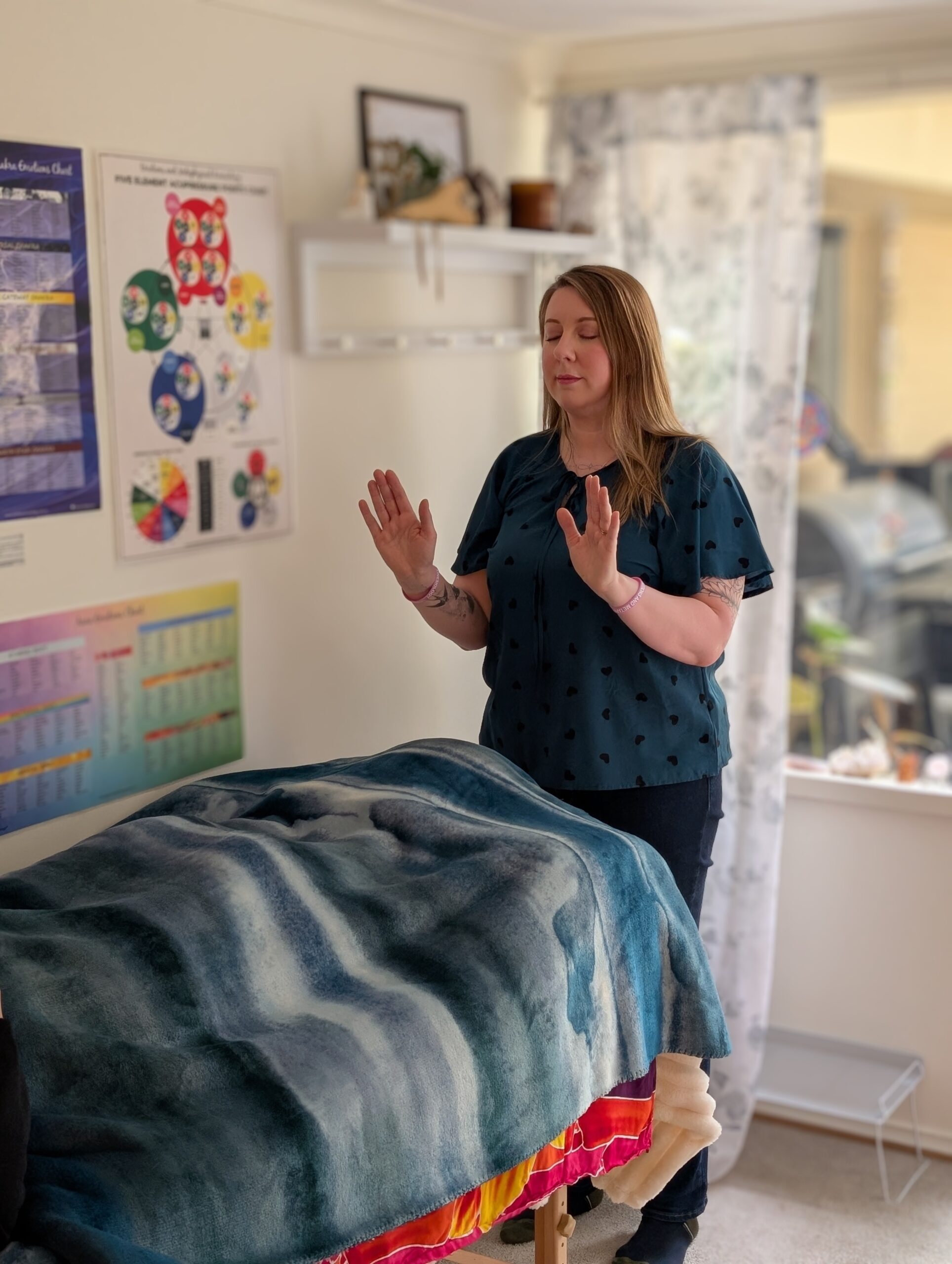Kath Whitehorn performing a kinesiology session with a client relaxing on a treatment table at Hill Tribe Healing.