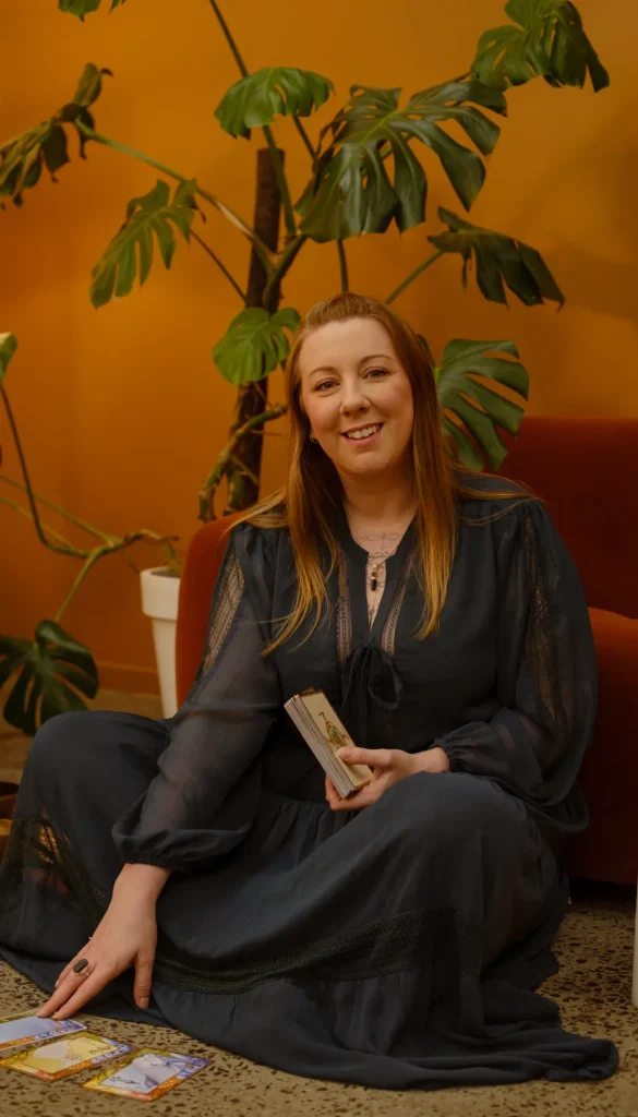 Kath Whitehorn seated with a deck of cards in a warmly lit room