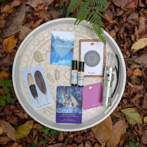 Cards, crystals and small remedy bottles arranged on a round tray among autumn leaves
